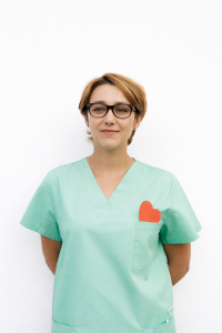 Profesional sanitaria con uniforme verde y gafas sobre fondo blanco.