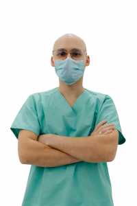 Profesional sanitario con uniforme verde, mascarilla y gafas en el interior de una clínica moderna